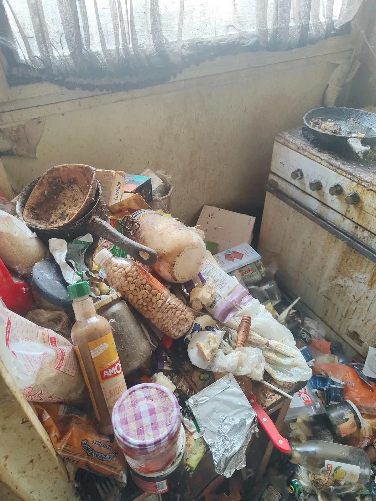 Cuisine fortement encombrée d’objets et de déchets avant nettoyage